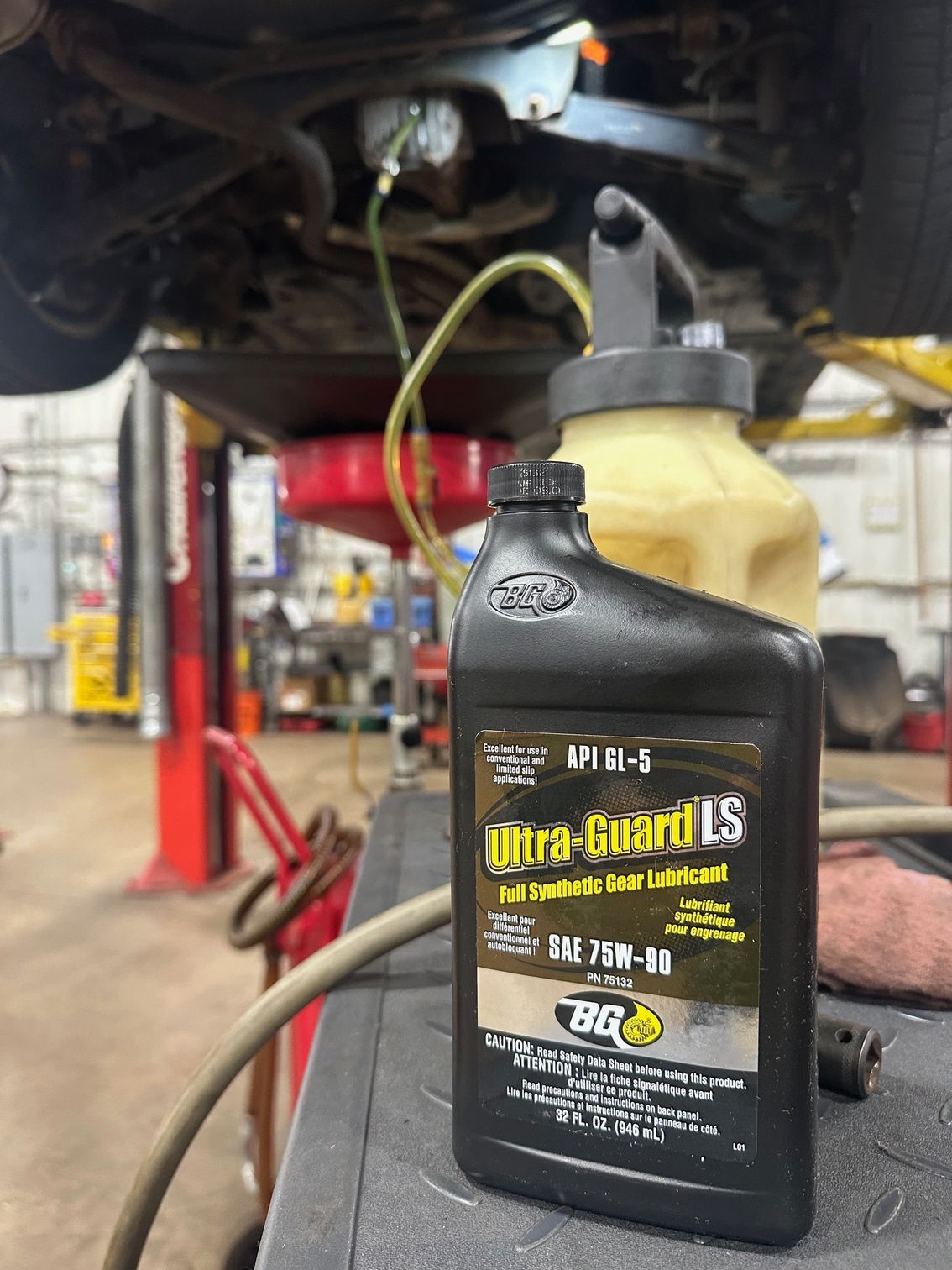 Automotive gear oil in black container in front of pump machine used in differential servic.