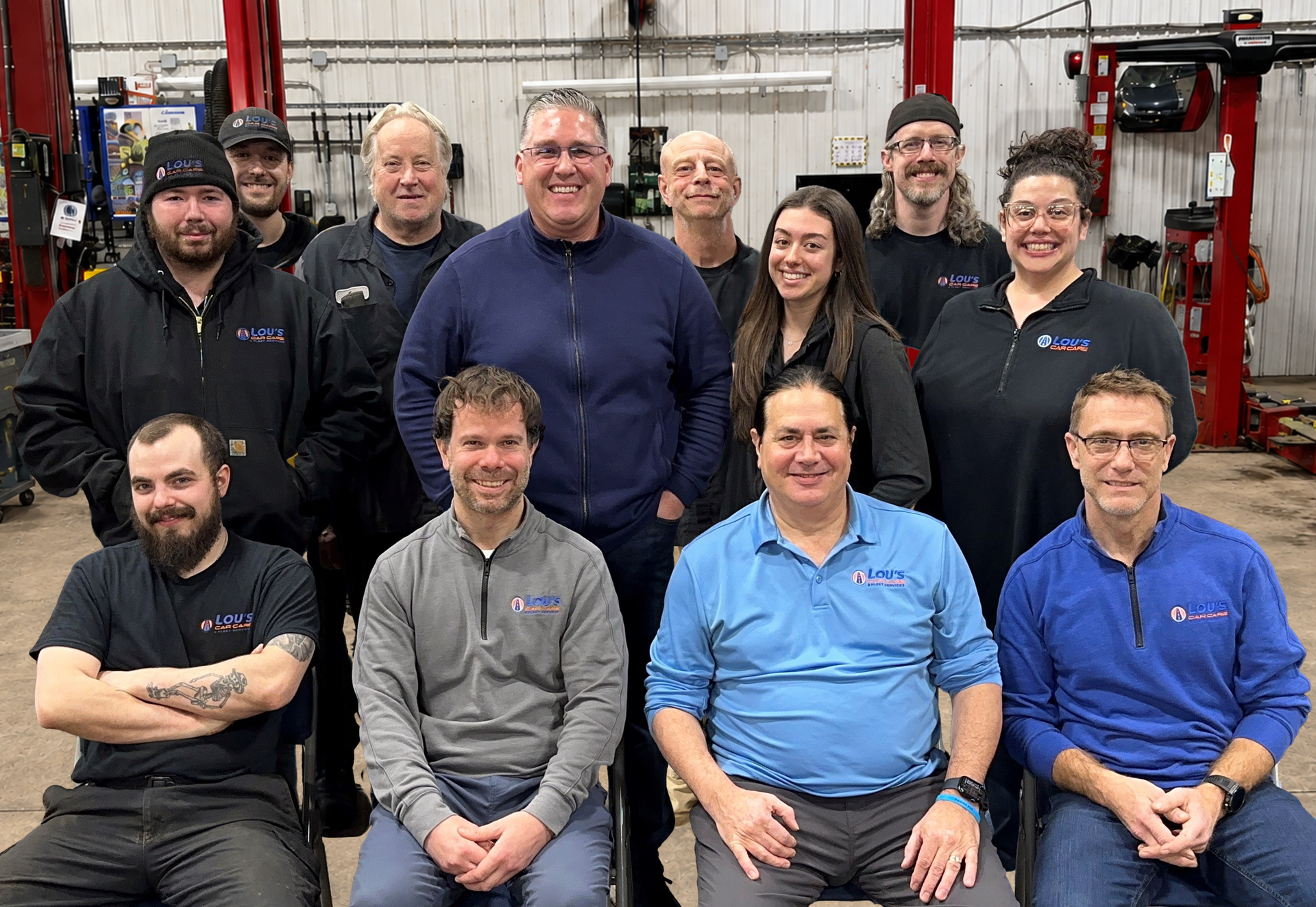 A group of people are posing for a picture in a garage. | Lou's Car Care Center