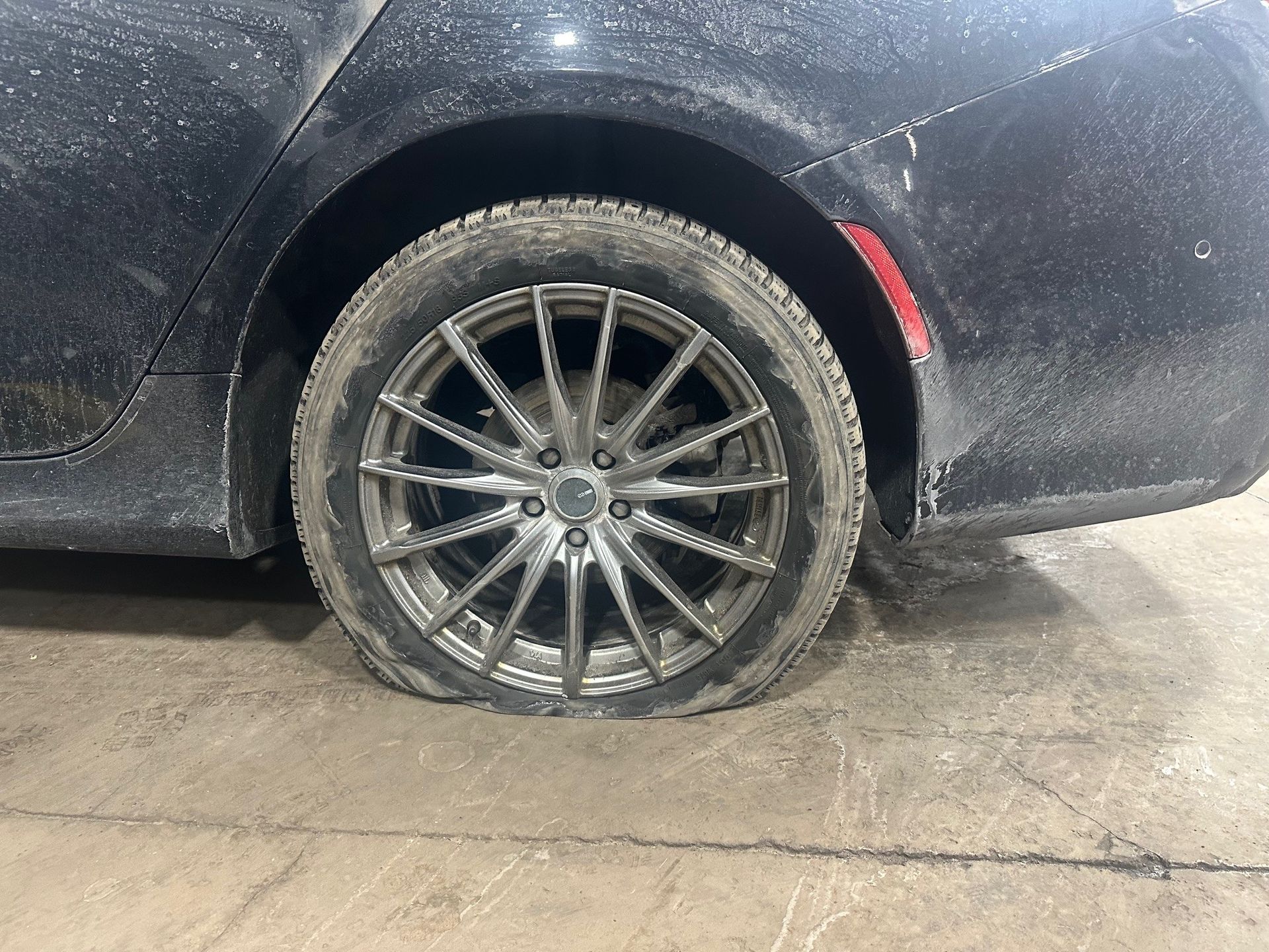 Flat tire on black vehicle in the shop | Lou's Car Care Center, Inc.
