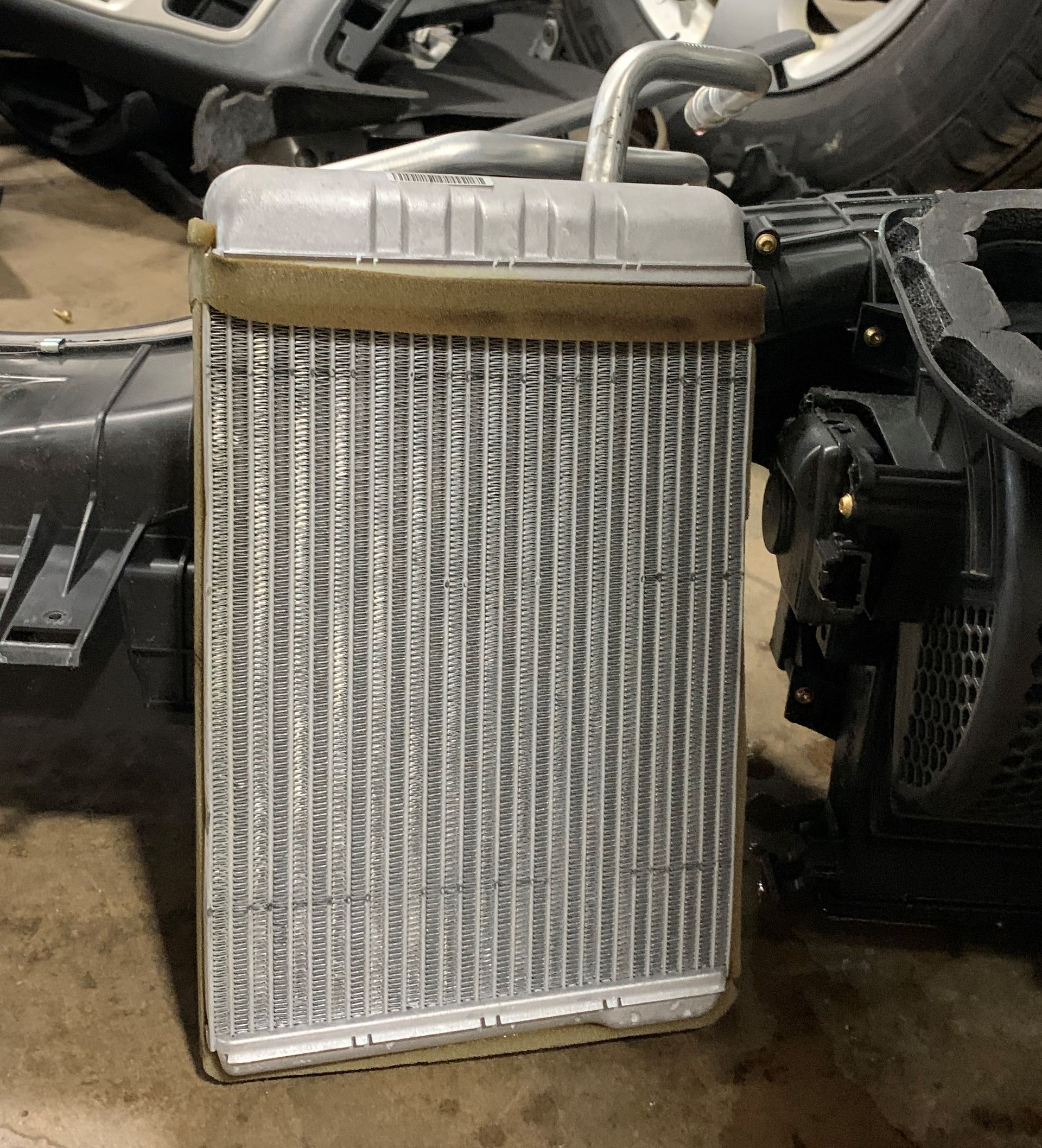 A radiator is sitting on the ground next to a car. | Lou's Car Care Center Inc.