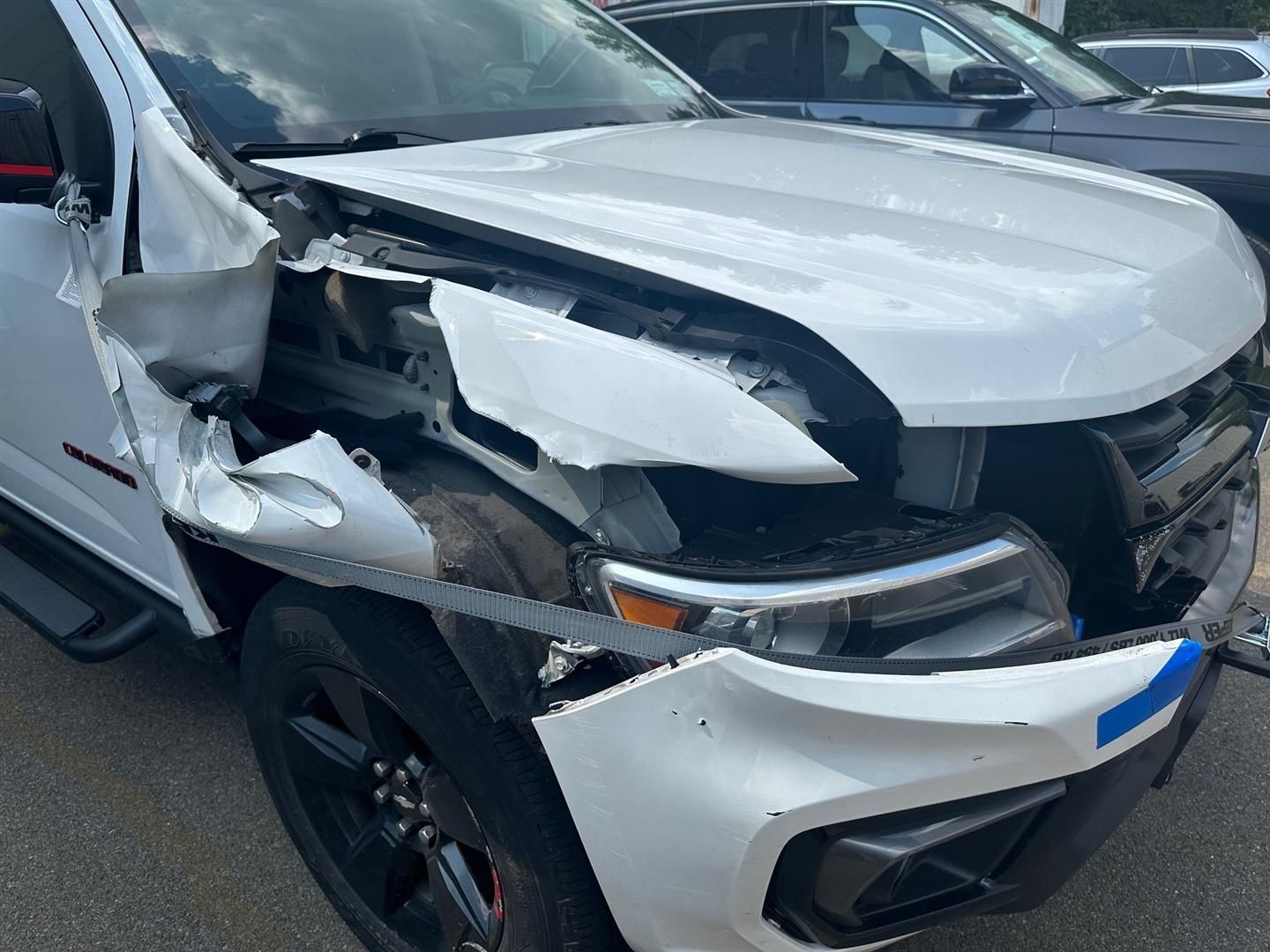 A white truck with a damaged front end is parked on the side of the road. | | Lou's Car Care Center, Inc.