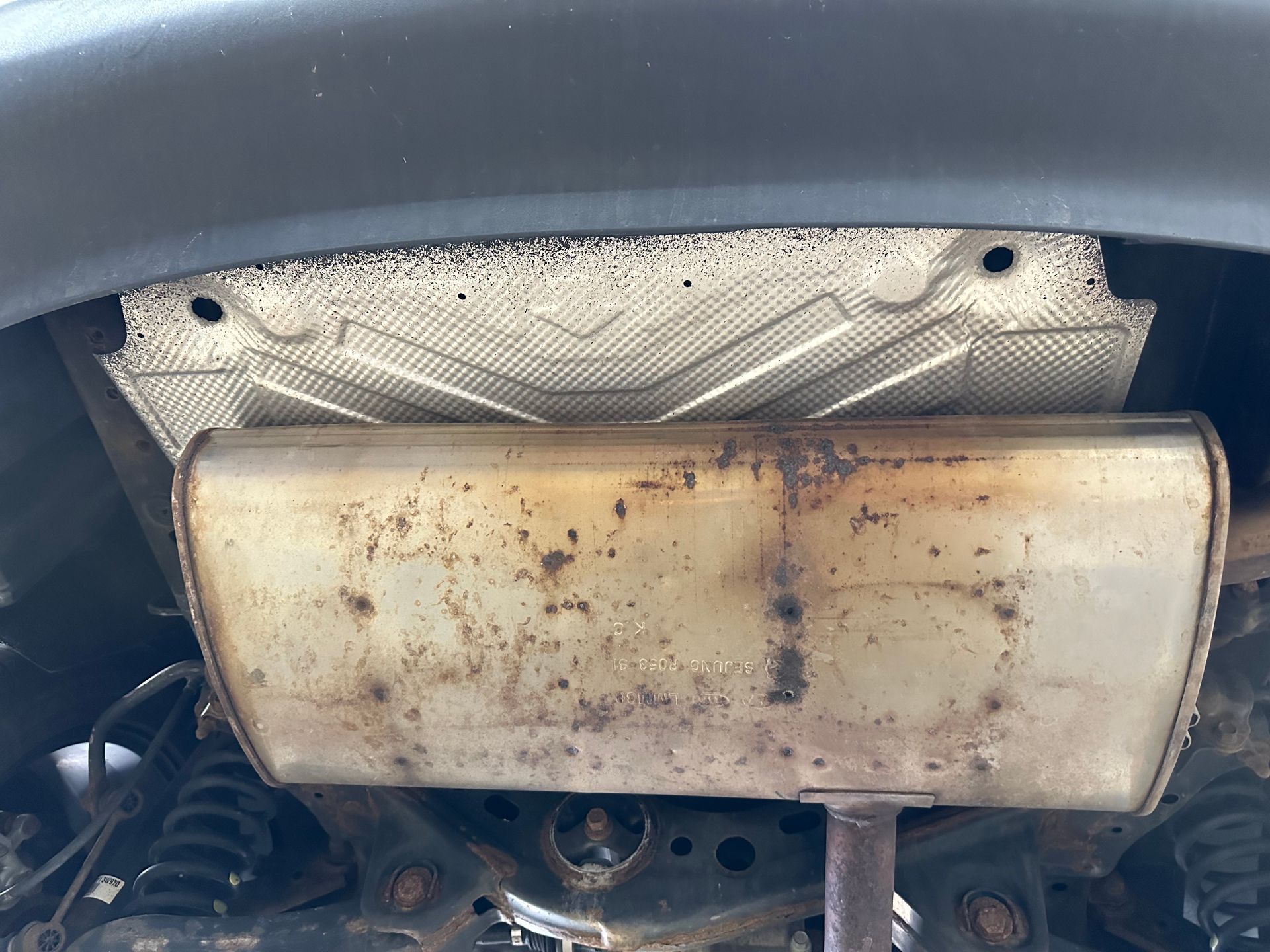 A close up of a rusty exhaust pipe on the underside of a car. | Lou's Car Care Center