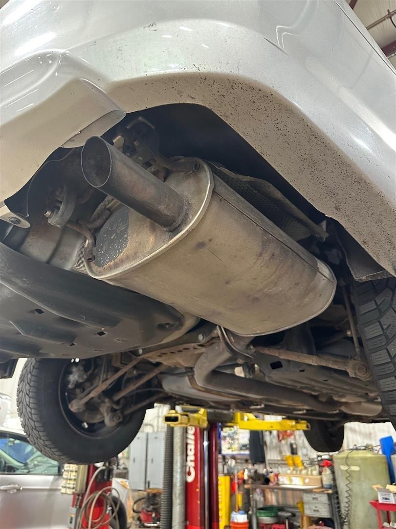 A car is sitting on a lift in a garage. | Lou's Car Care Center, Inc.