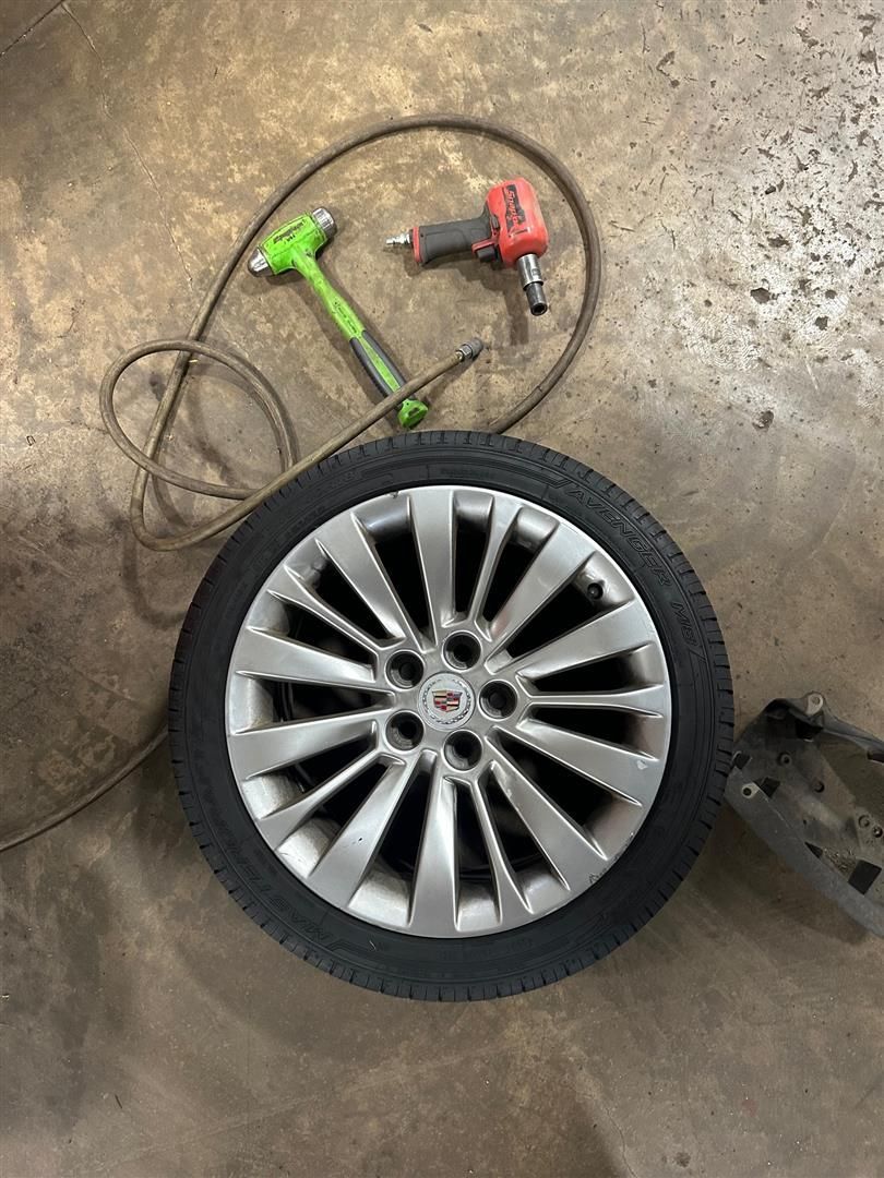 A tire is sitting on the ground next to a tool. | Lou's Car Care Center, Inc.