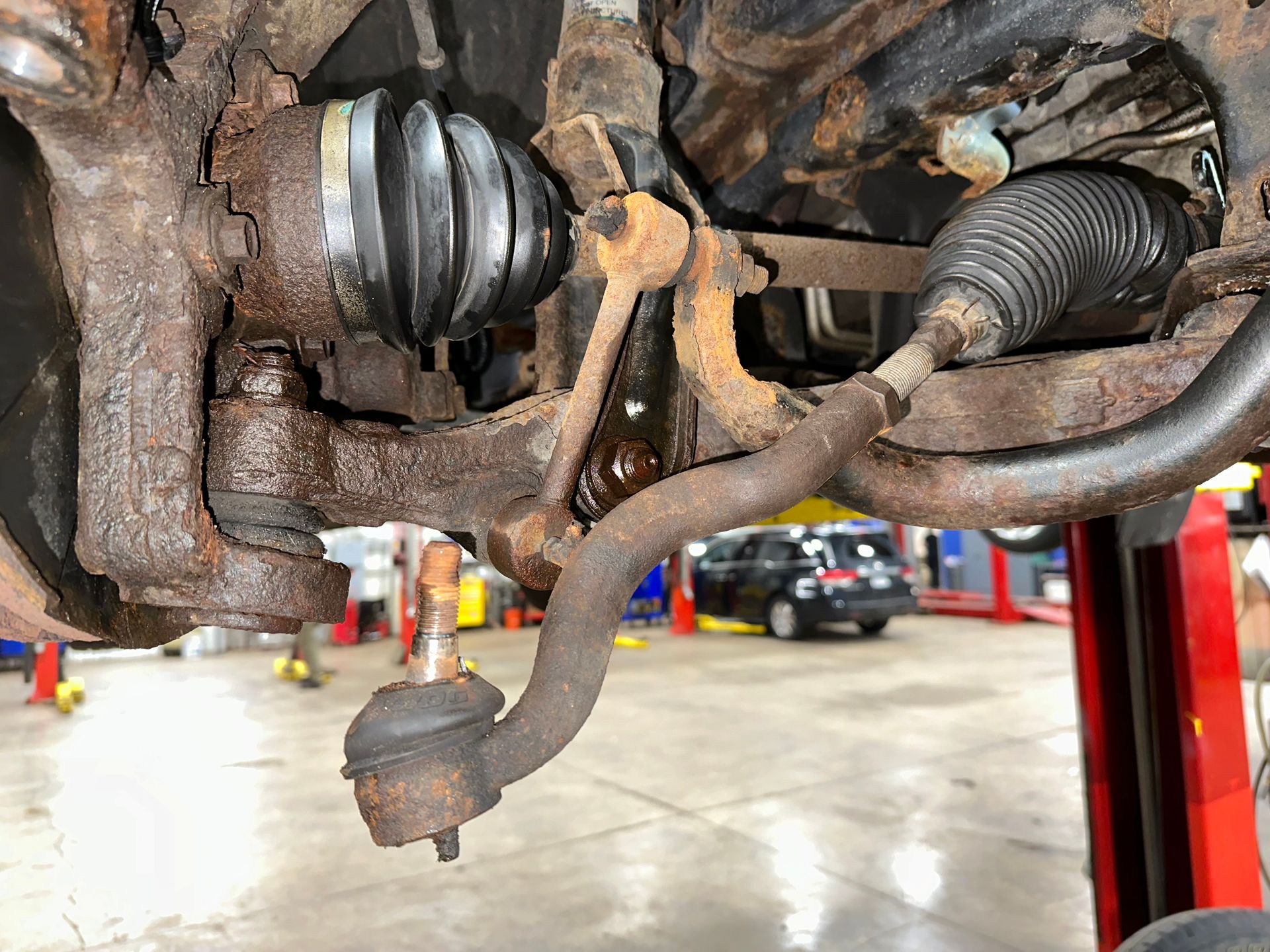 A close up of a rusty suspension system on a car in a garage. | Lou's Car Care Center, Inc.