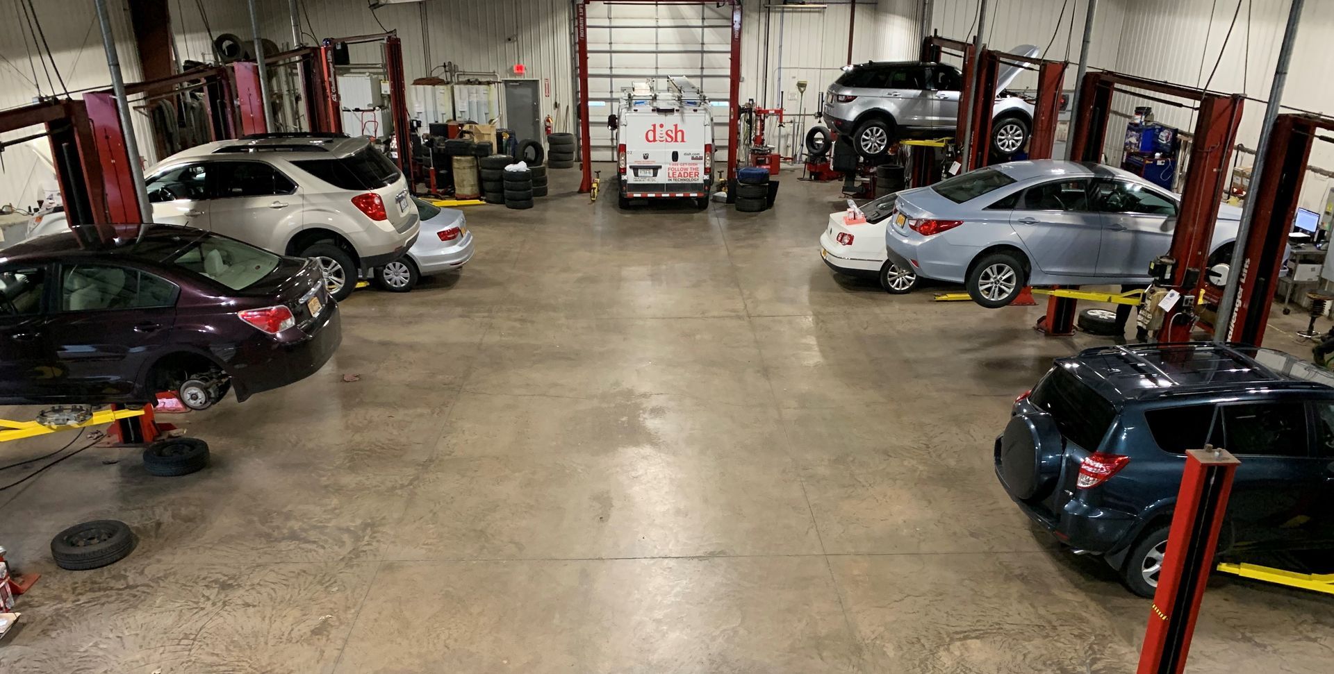 A lot of cars are sitting on lifts in a garage. | Lou's Car Care Center, Inc.