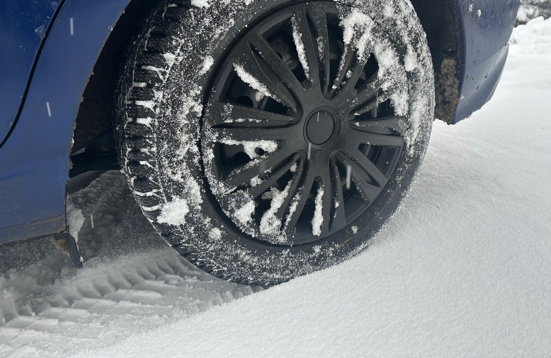 Snow Tire on Blue Car in Snow