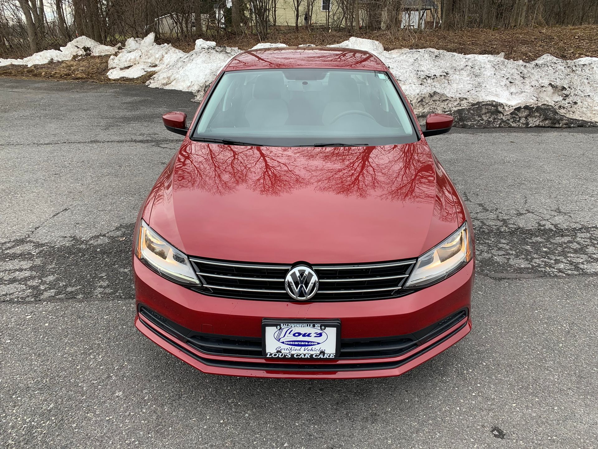 A red volkswagen jetta is parked in a parking lot. | Lou's Car Care Center Inc.