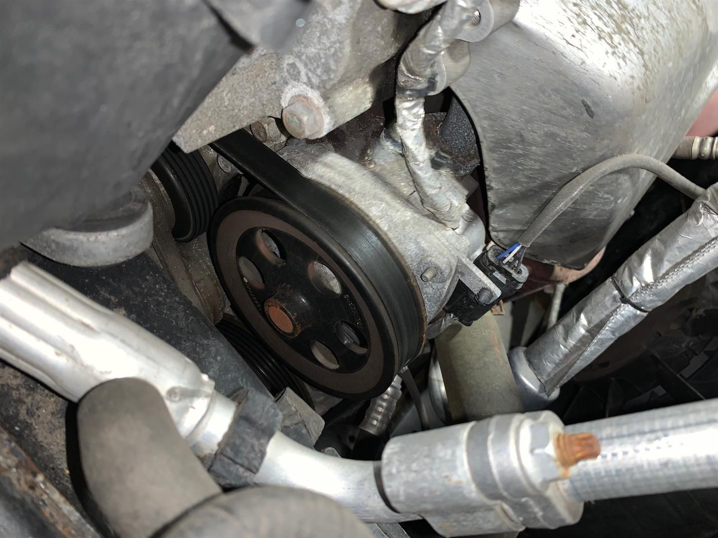 A person is working on a car engine with a wrench. | Lou's Car Care Center Inc.