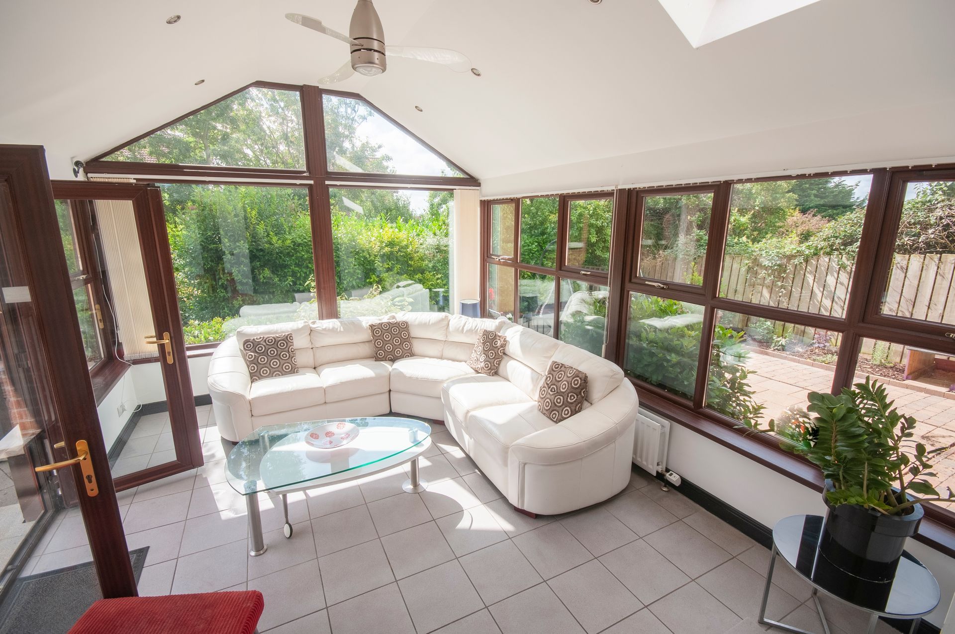 Sunroom with white sectional sofa and glass coffee table