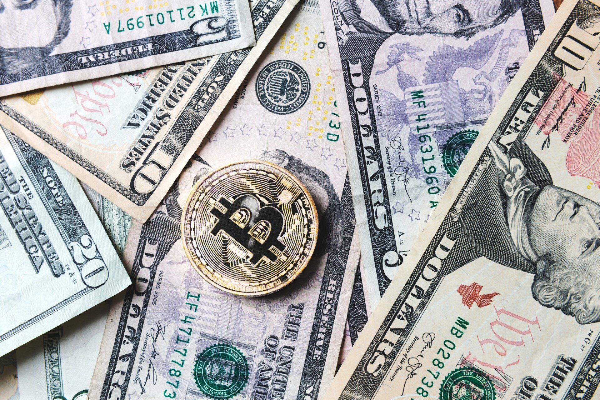 Bitcoin coin on top of US dollar bills.