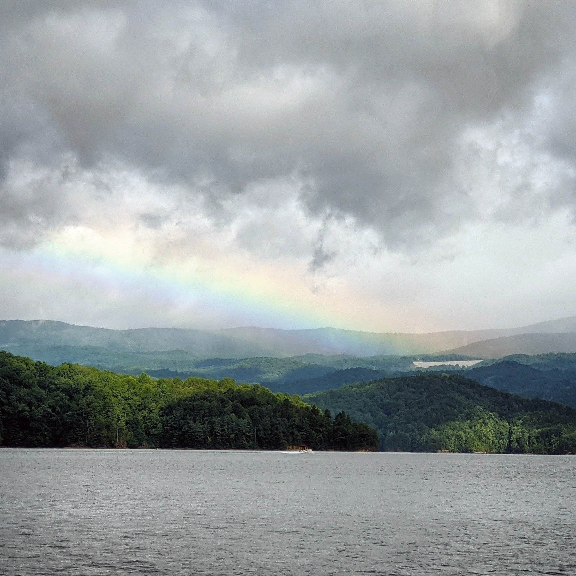 A rainbow over a lake and forested hills in North Carolina