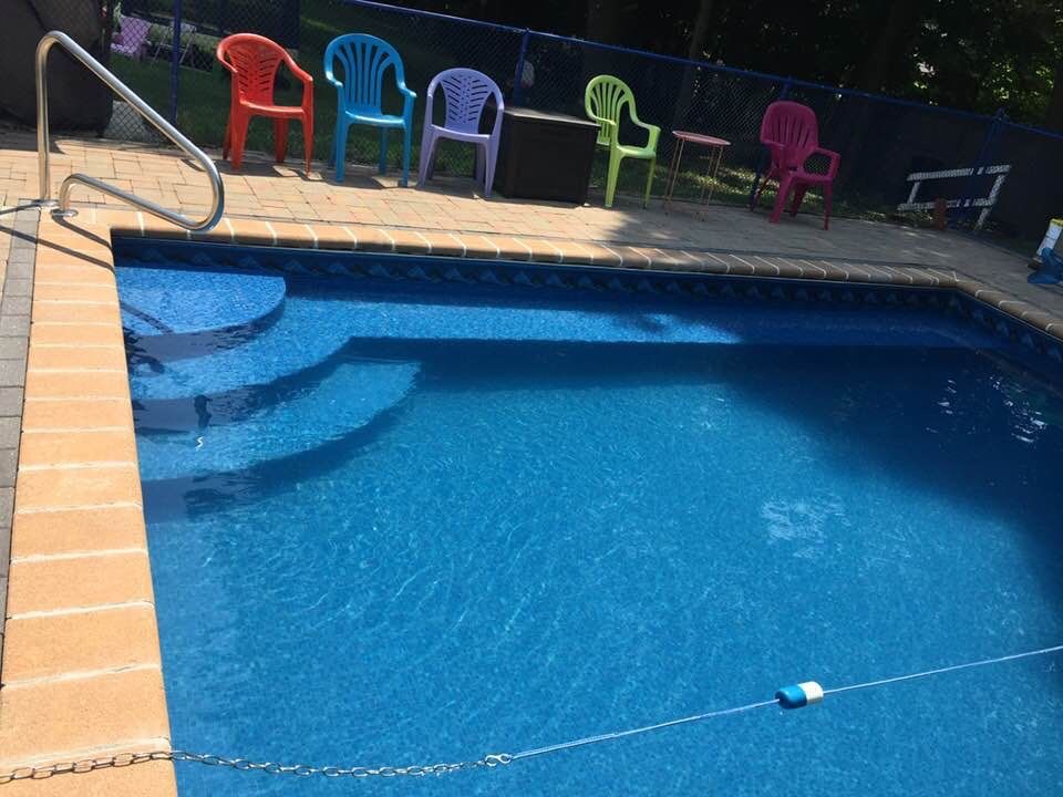 Above-ground pool in a backyard with a patio, covered porch, and a two-story house.