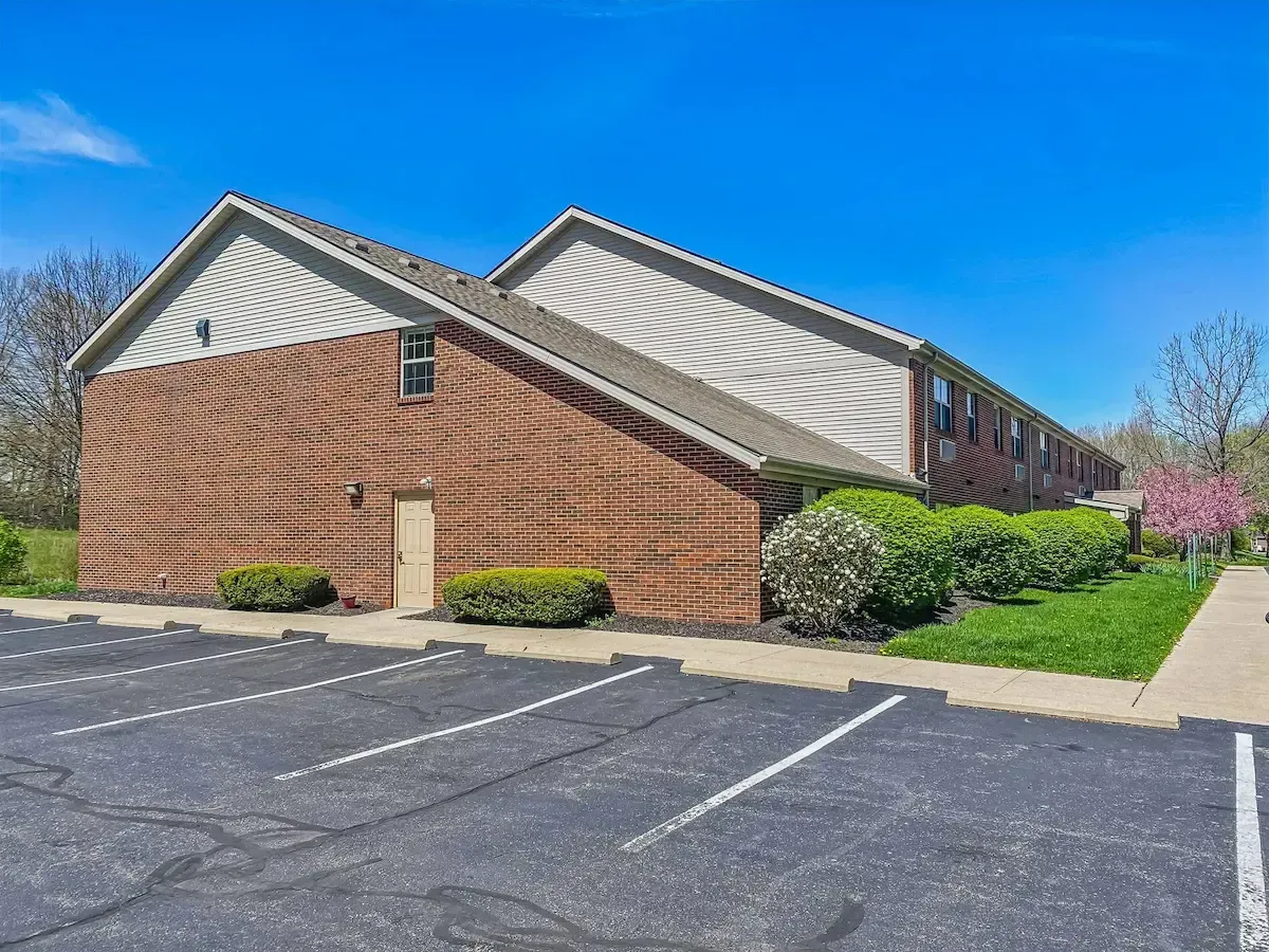 A brick apartment building with a parking lot in front of it.