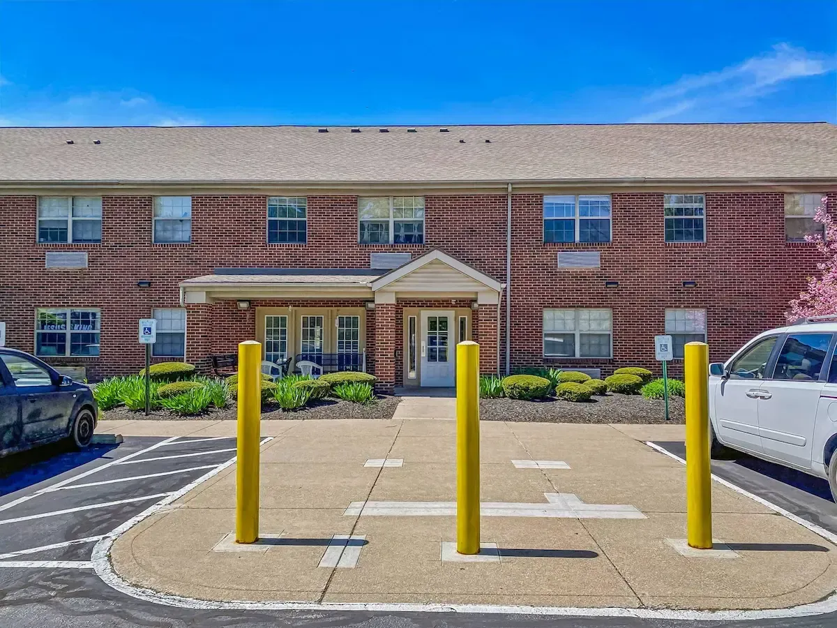 A parking lot in front of a large brick building with cars parked in front of it.