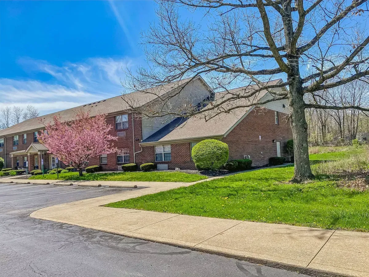 A brick apartment building with a tree in front of it.