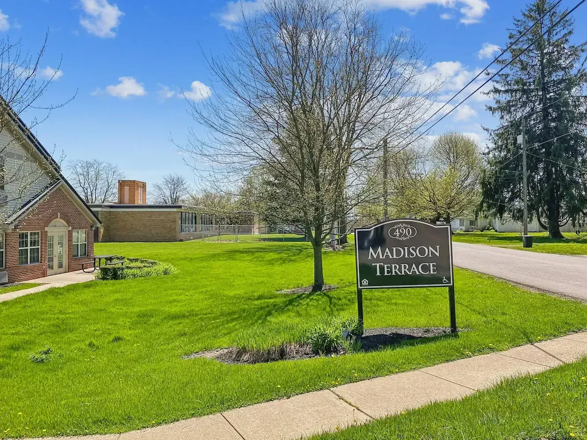 A sign for madison terrace is in the middle of a lush green field.