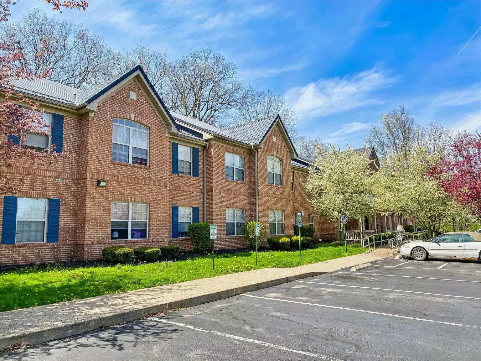 A large brick apartment building with a parking lot in front of it.