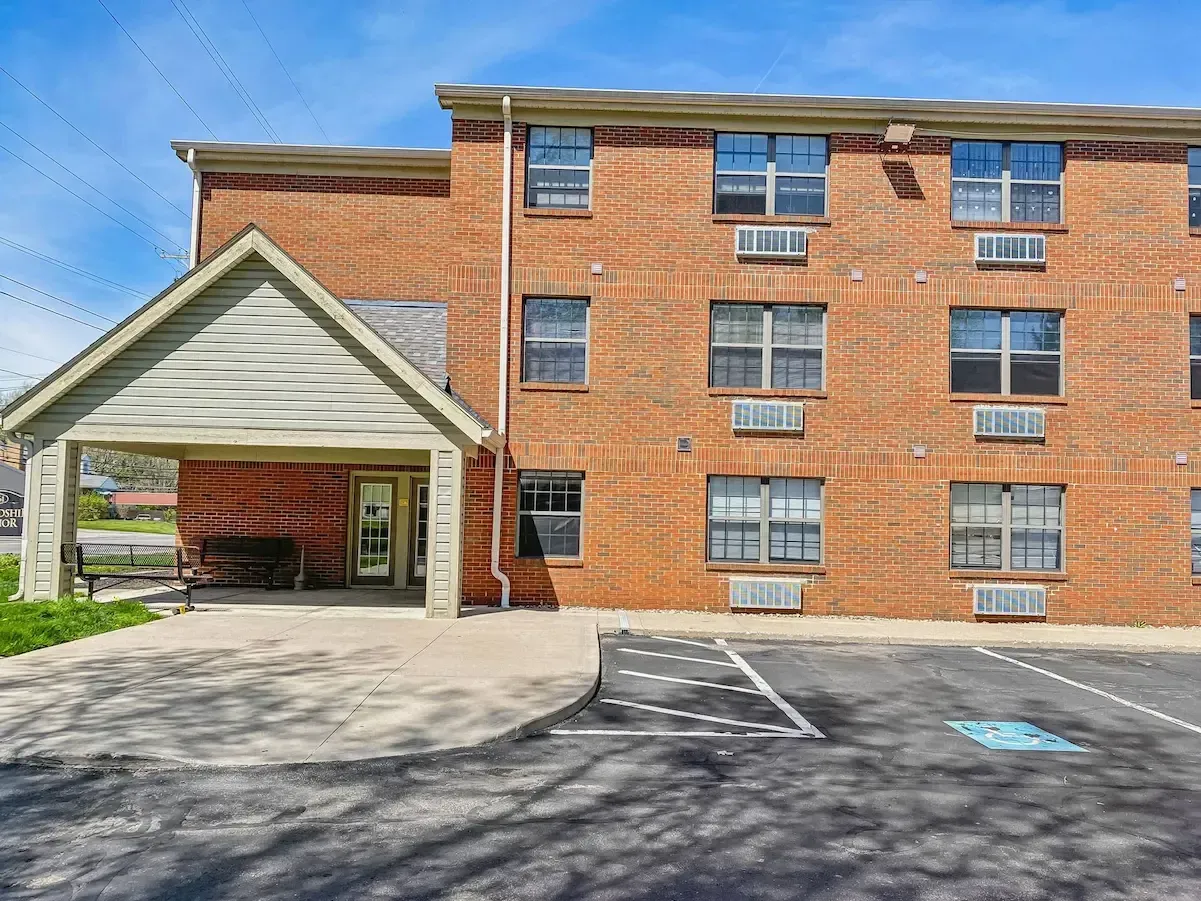 A large brick apartment building with a handicapped parking spot in front of it.