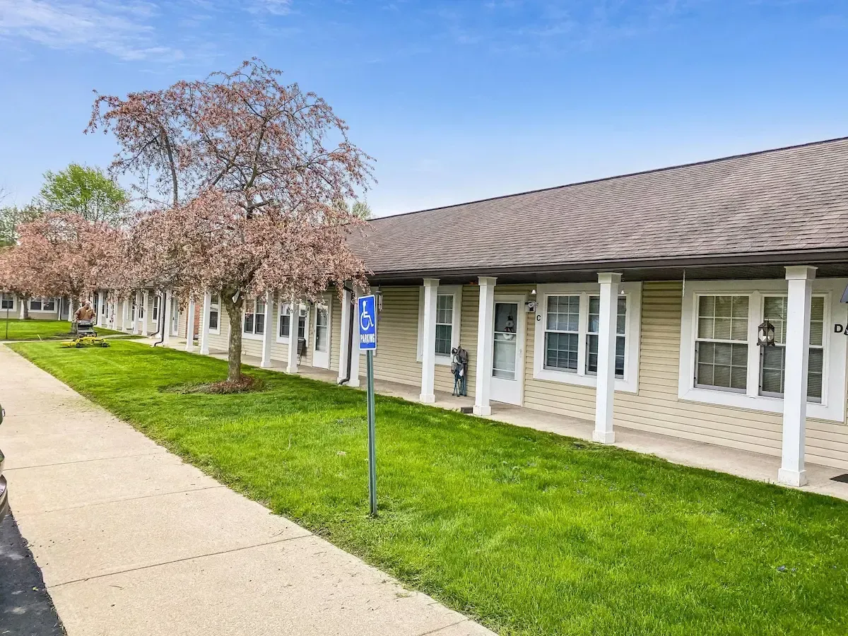 A row of houses with a sidewalk and trees in front of them.