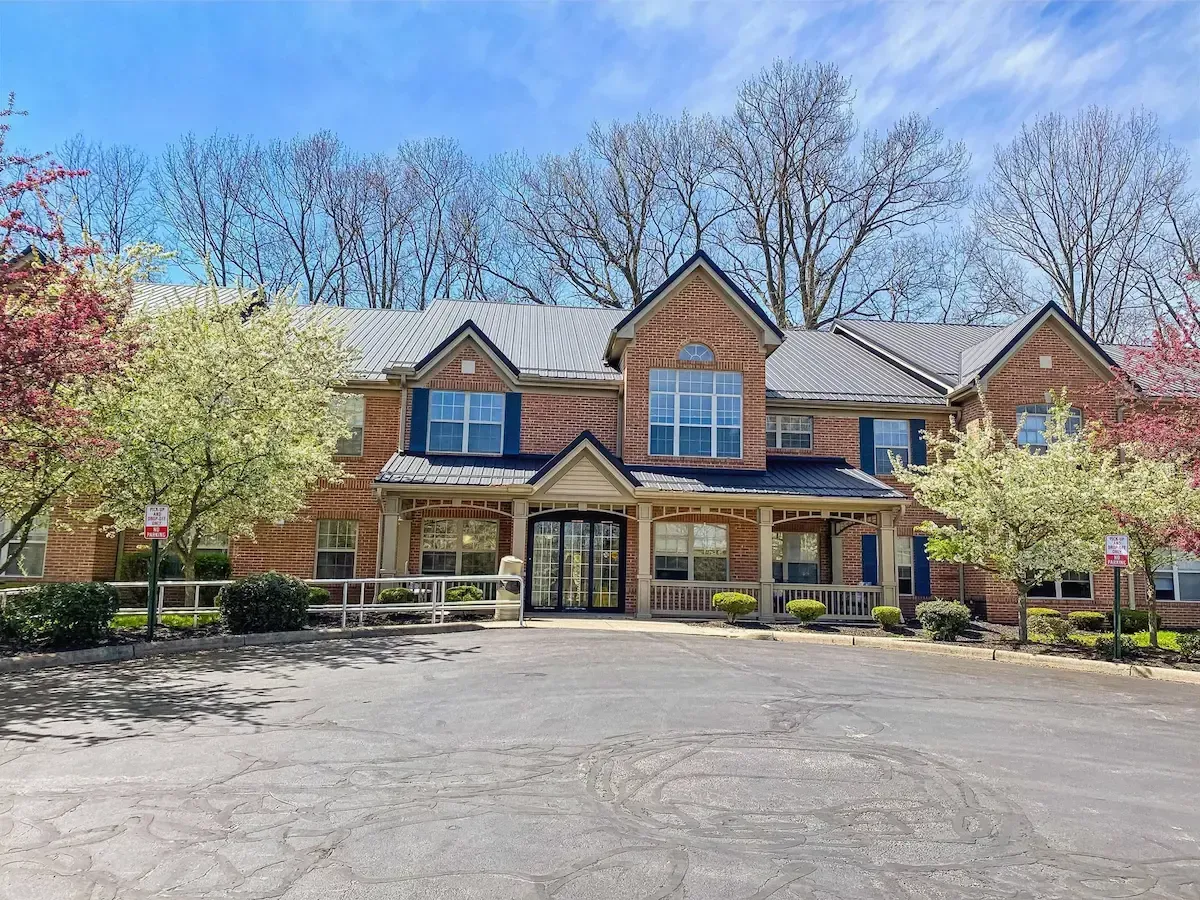A large brick house with a lot of windows and trees in front of it.
