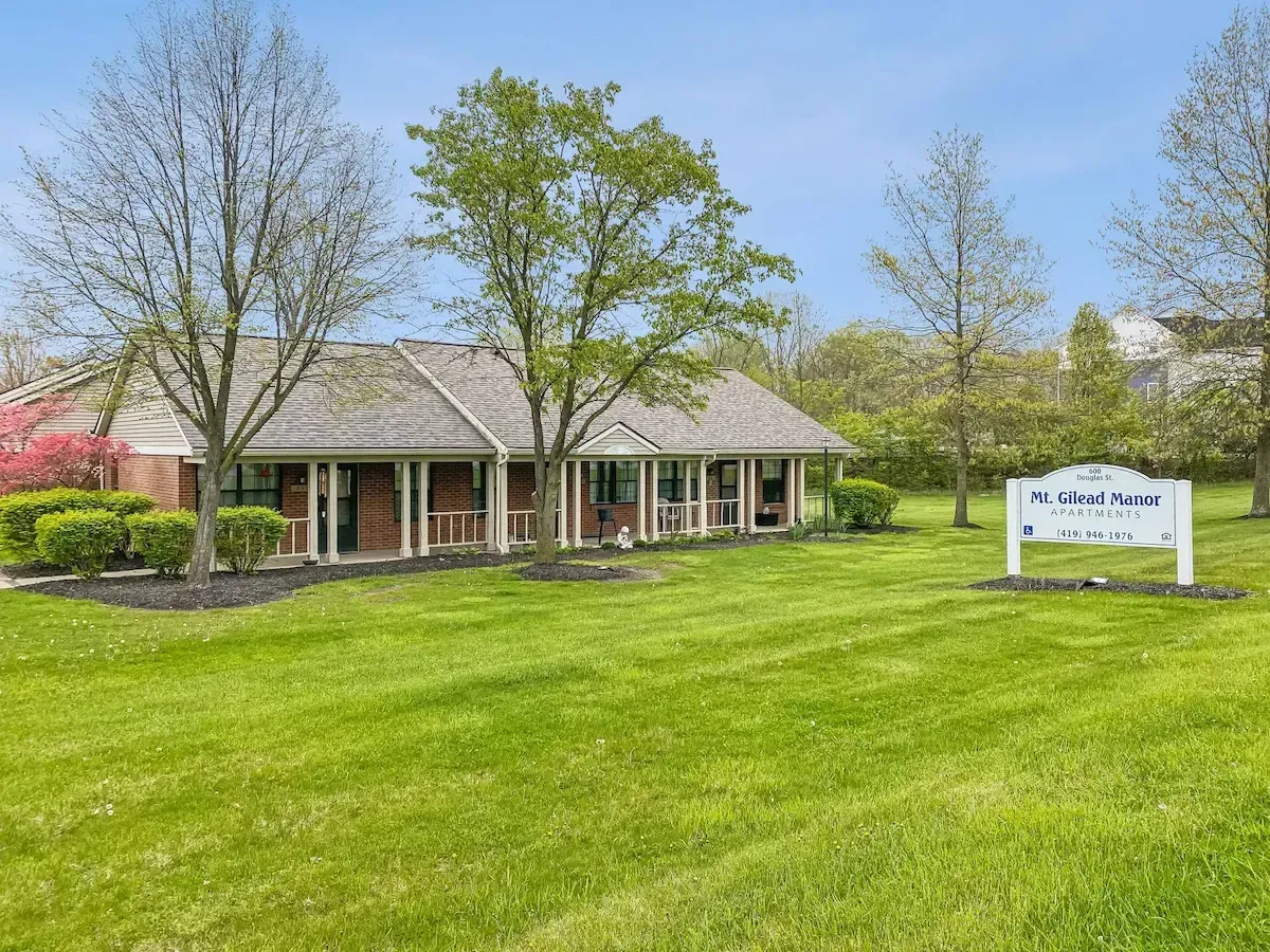 A brick house is sitting in the middle of a lush green field.