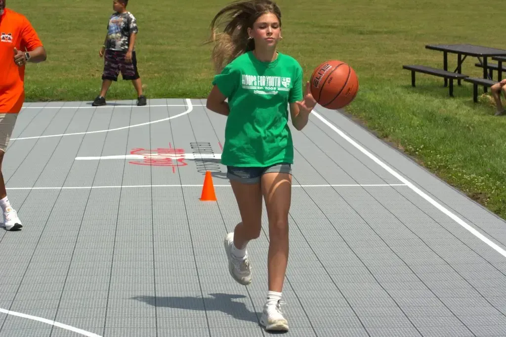 A girl wearing a green t-shirt that says brooklyn is holding a basketball