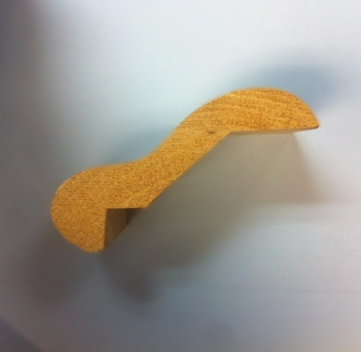 Wooden decorative molding profile. Curved, L-shaped profile, natural wood color.