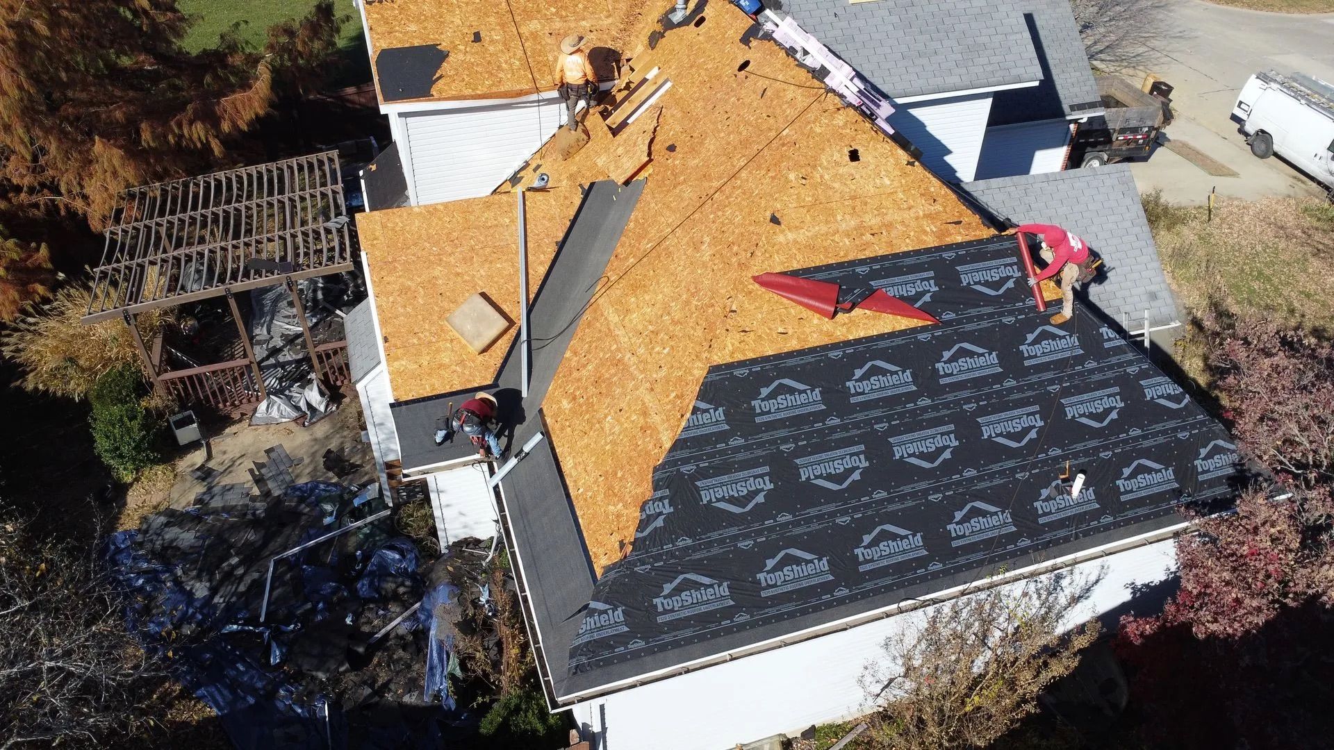 Roofers installing new shingles on a house roof.