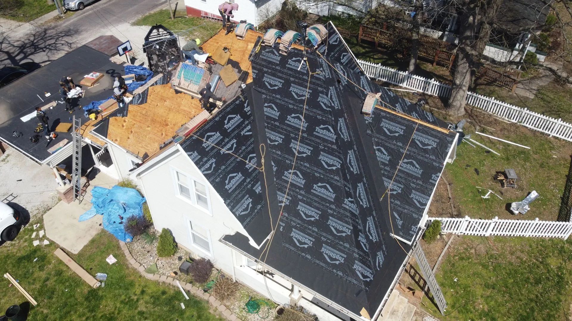 Aerial view of a house with a partially replaced roof. Roofing work is in progress.