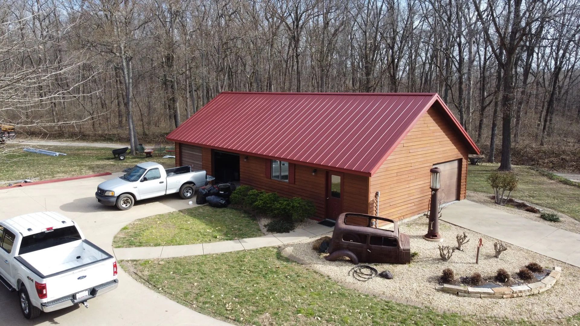 Red metal roof brown garage with two trucks parked outside,