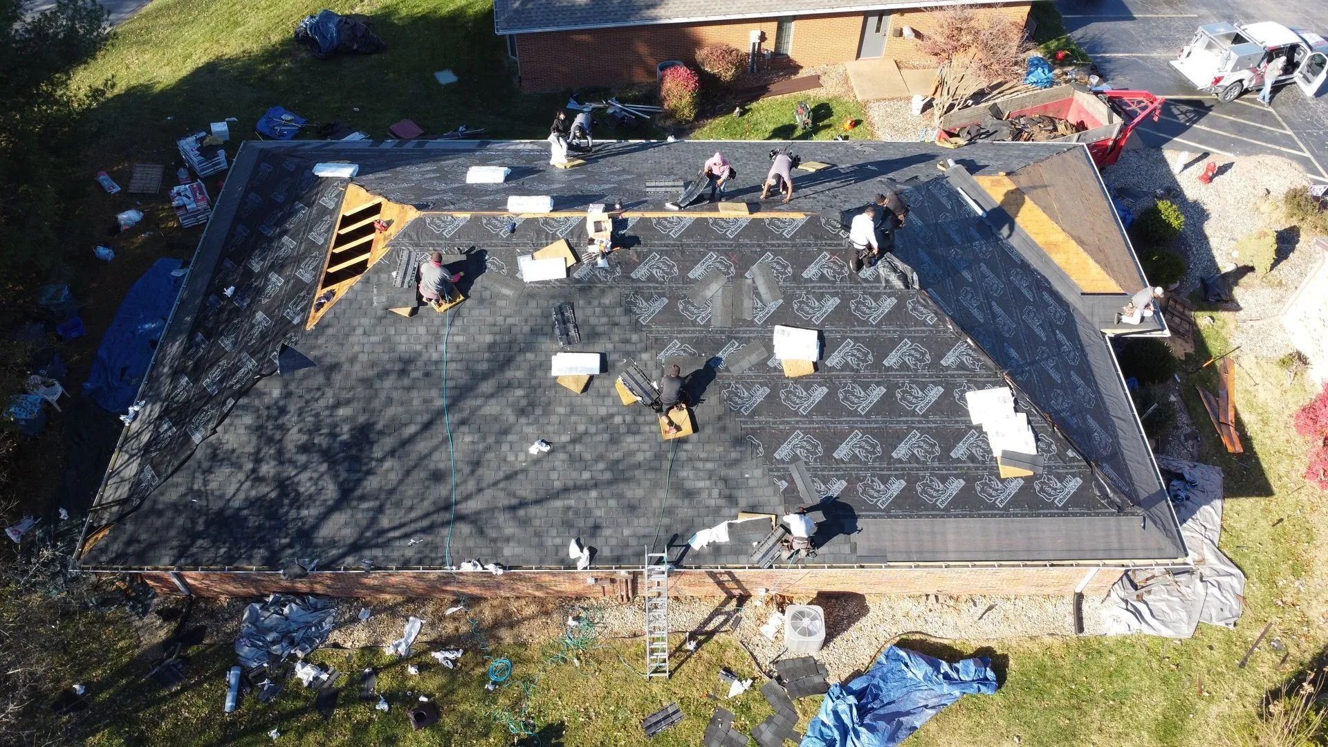 Roofing crew working on a dark roof, surrounded by tools and materials.