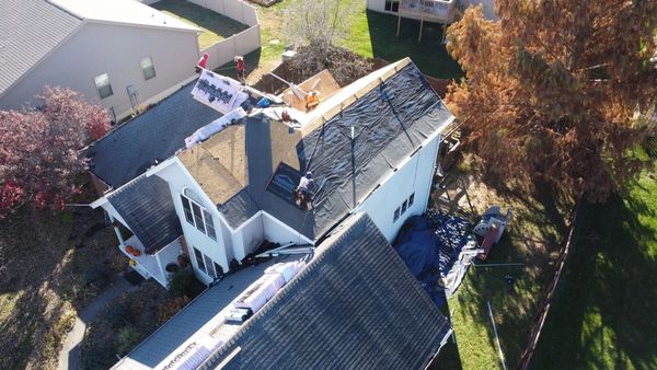 Aerial view of a house being re-roofed; roof partially covered with shingles, others removed.