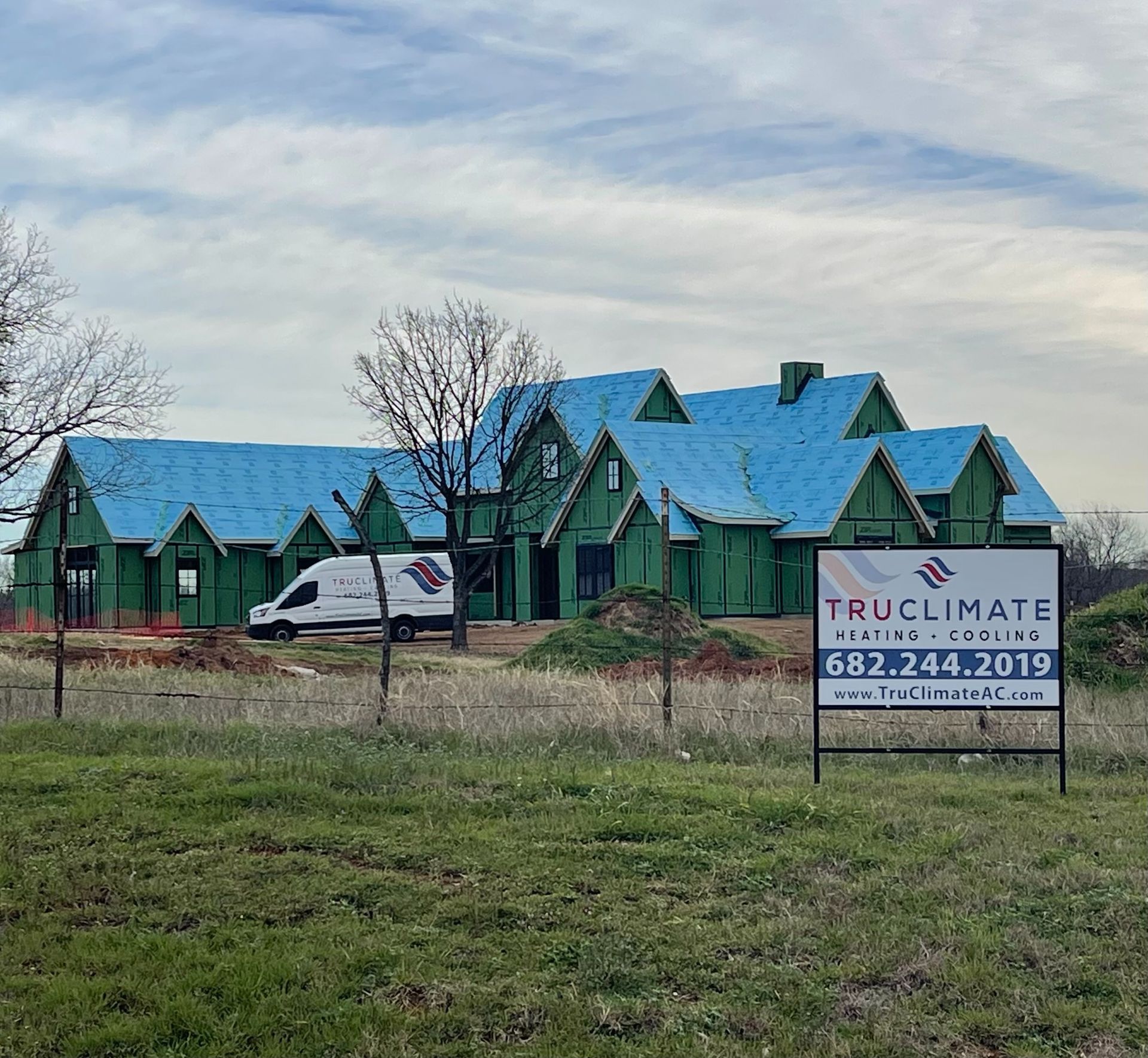A house under construction with blue roofs and a sign that says truclimate