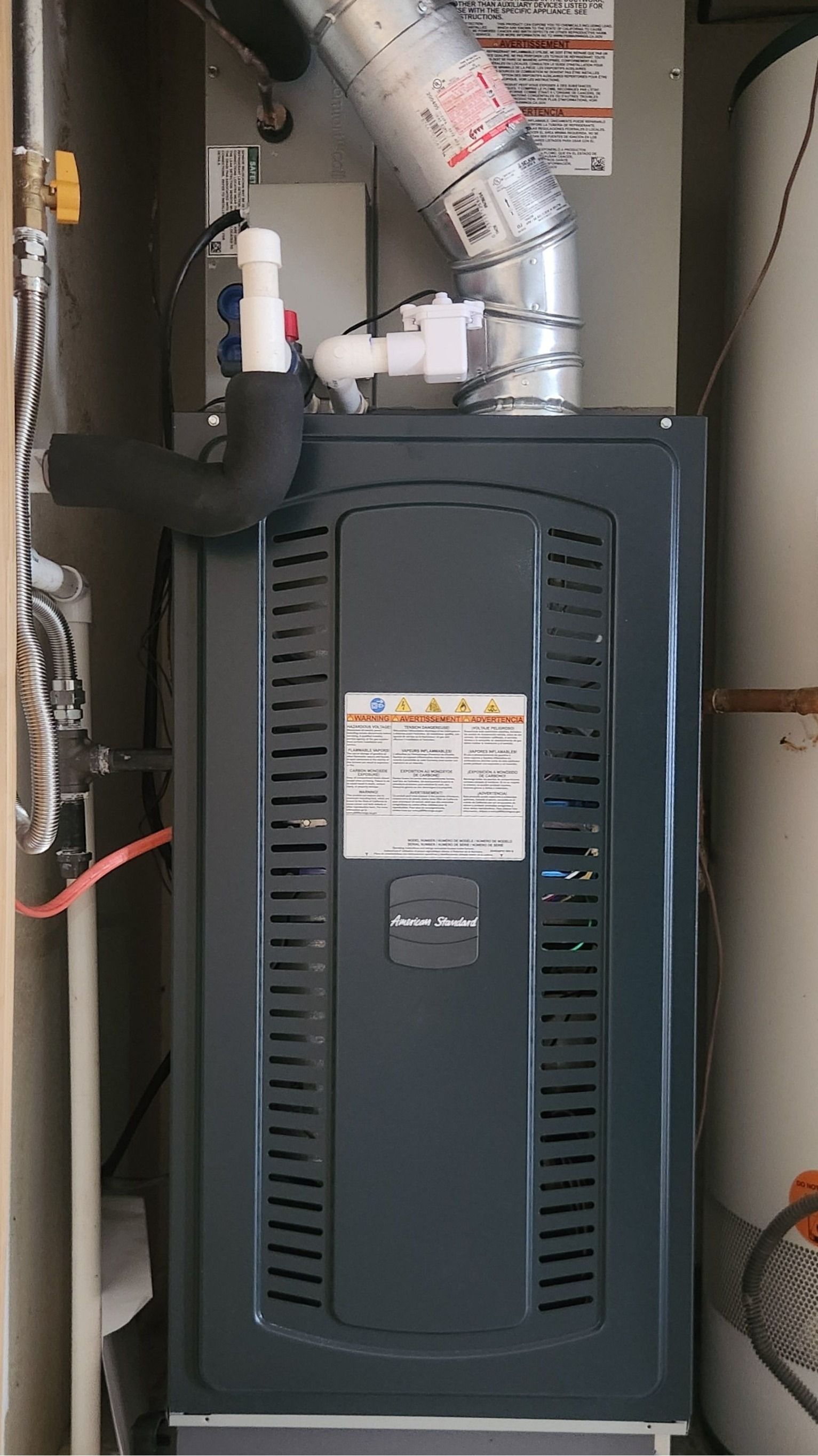 A gas heater is sitting in a room next to a water heater.