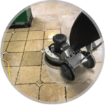 A floor buffer machine cleaning a light-colored tiled floor with dark grout lines.