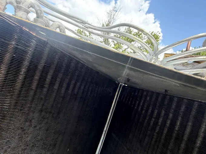 Close-up of black corrugated walls with a white metal railing above, viewed at an angle outdoors