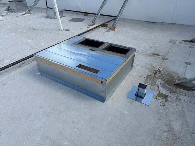 Low concrete platform with two rectangular openings and a metal edge in a rooftop or industrial area