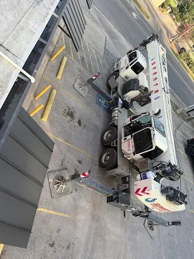 Overturned cement mixer truck in an industrial lot, with cones and equipment around it