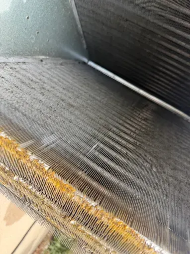 Close-up of a dirty metal air filter with dust and yellow debris along the edge