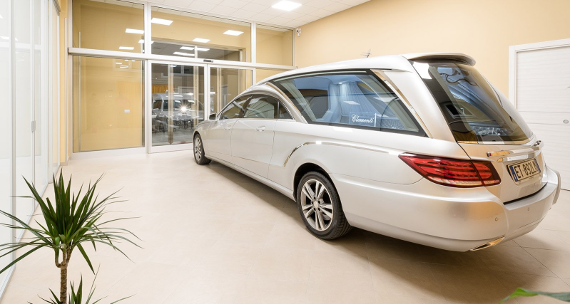 Silver sedan parked inside a bright showroom with glass walls and a potted plant nearby