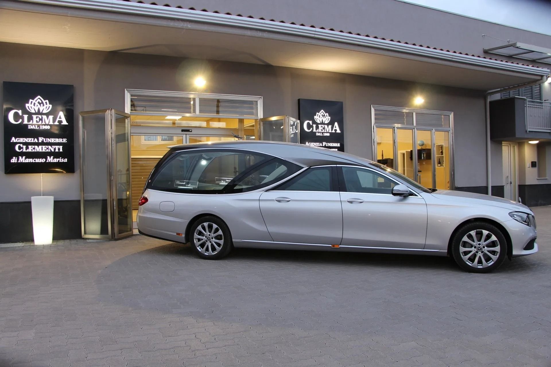 Silver station wagon parked outside a building entrance at dusk