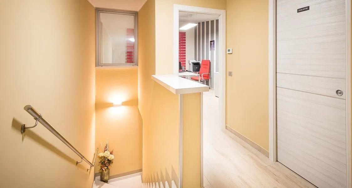 Bright stairwell with beige walls, white doors, and a small hallway opening to a kitchen counter.