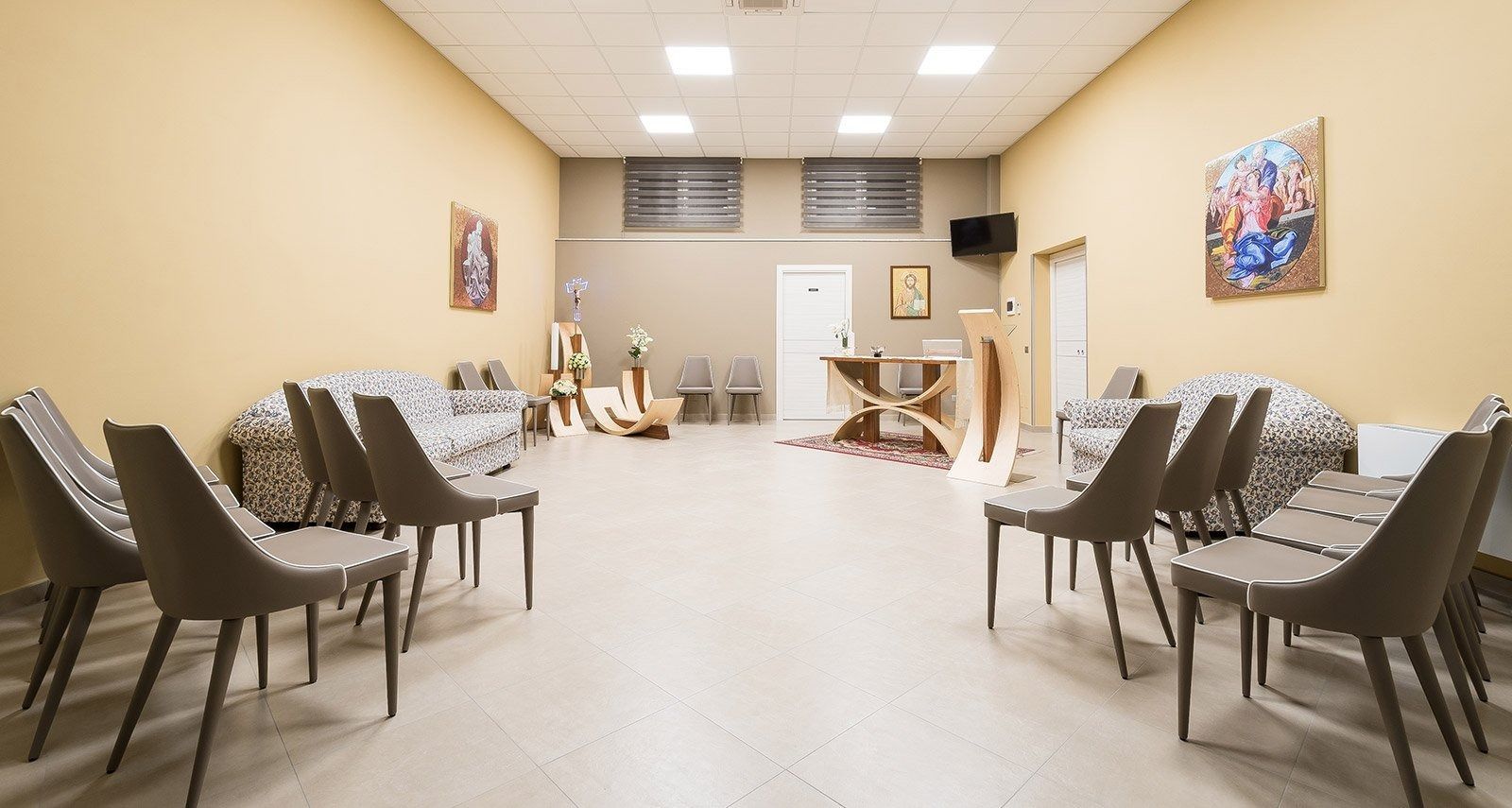 Empty waiting room with rows of brown chairs, beige walls, and bright overhead lights