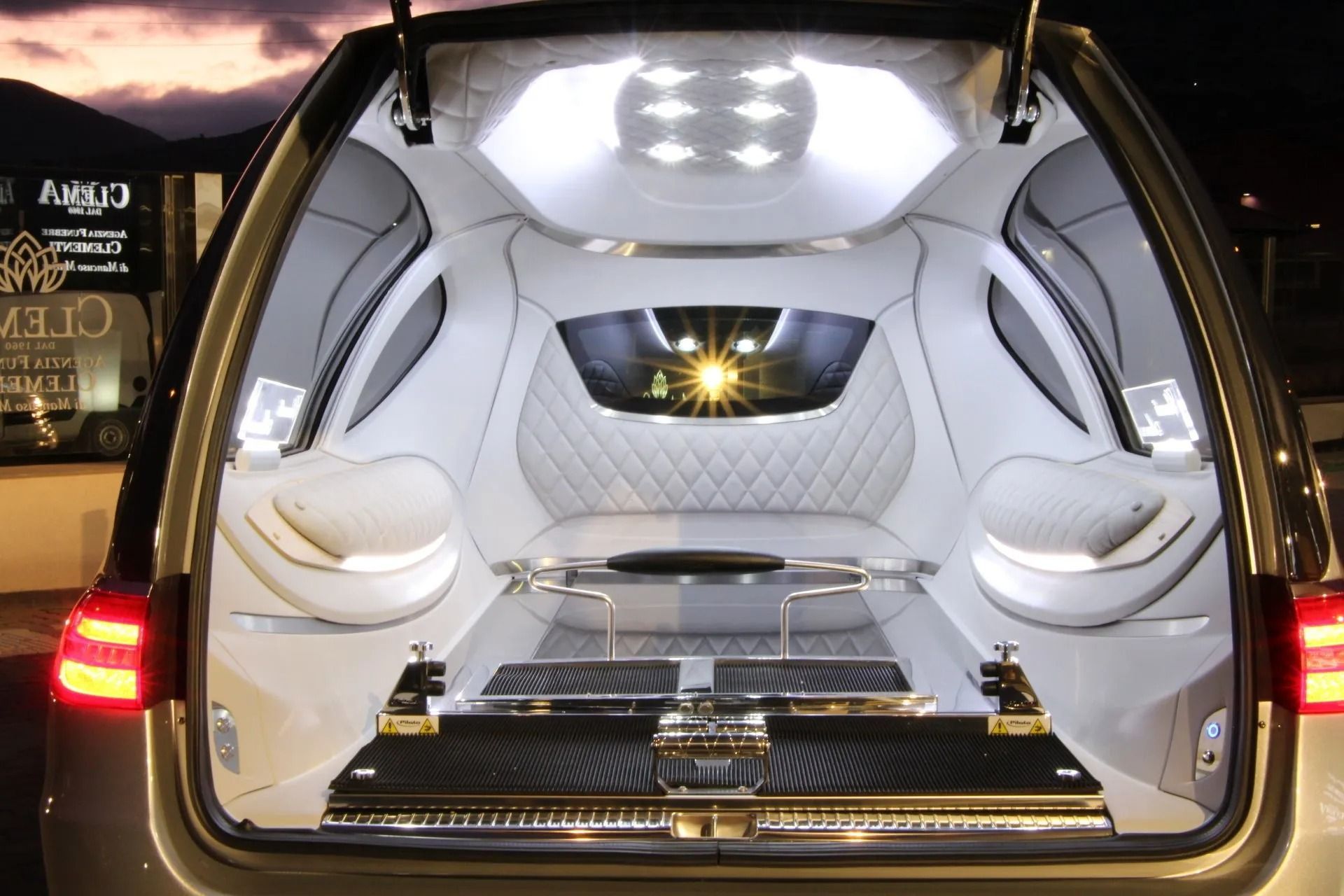 Open luxury van interior with white leather seating and illuminated ceiling at dusk