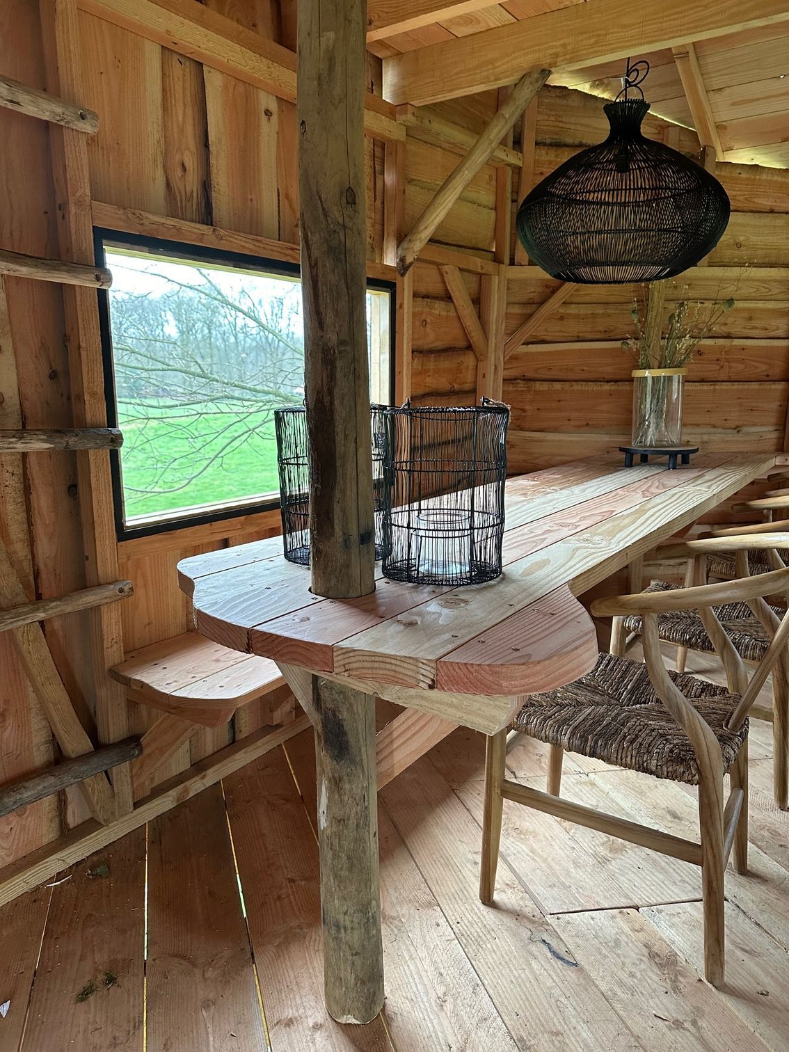 Een houten hut met een lange houten tafel en stoelen.