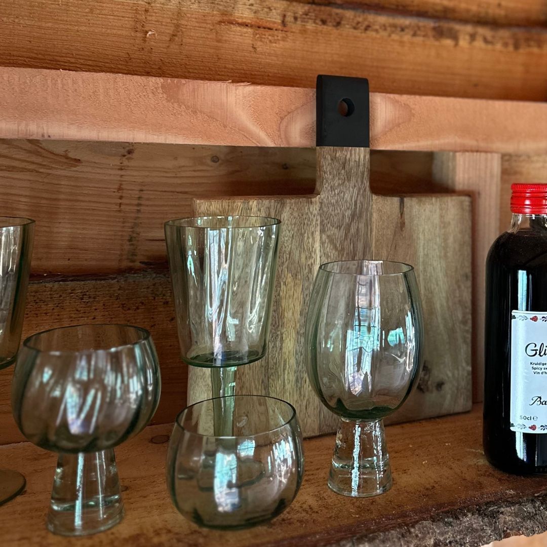 Glazen, snijplank en fles op een houten plank.