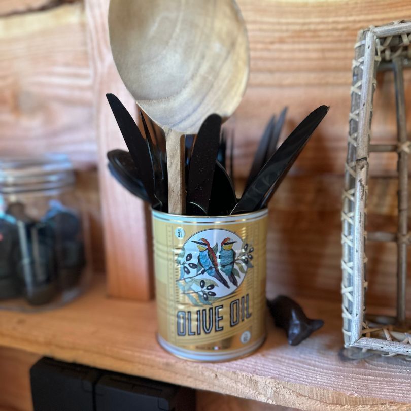 Houten lepel en bestek in een olijfolieblik, op een houten plank.