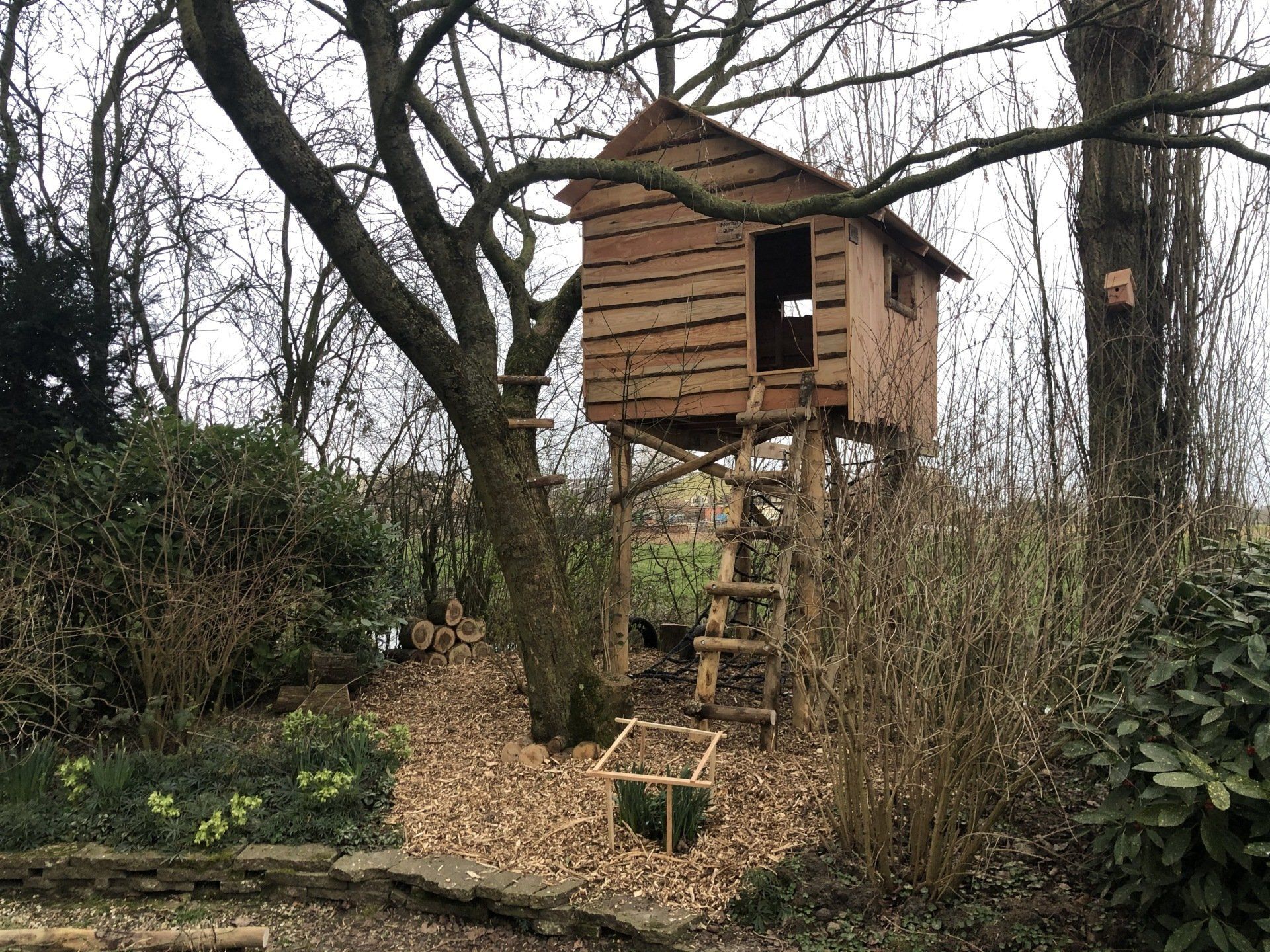 Midden in het bos staat een houten boomhut bovenop een boom.