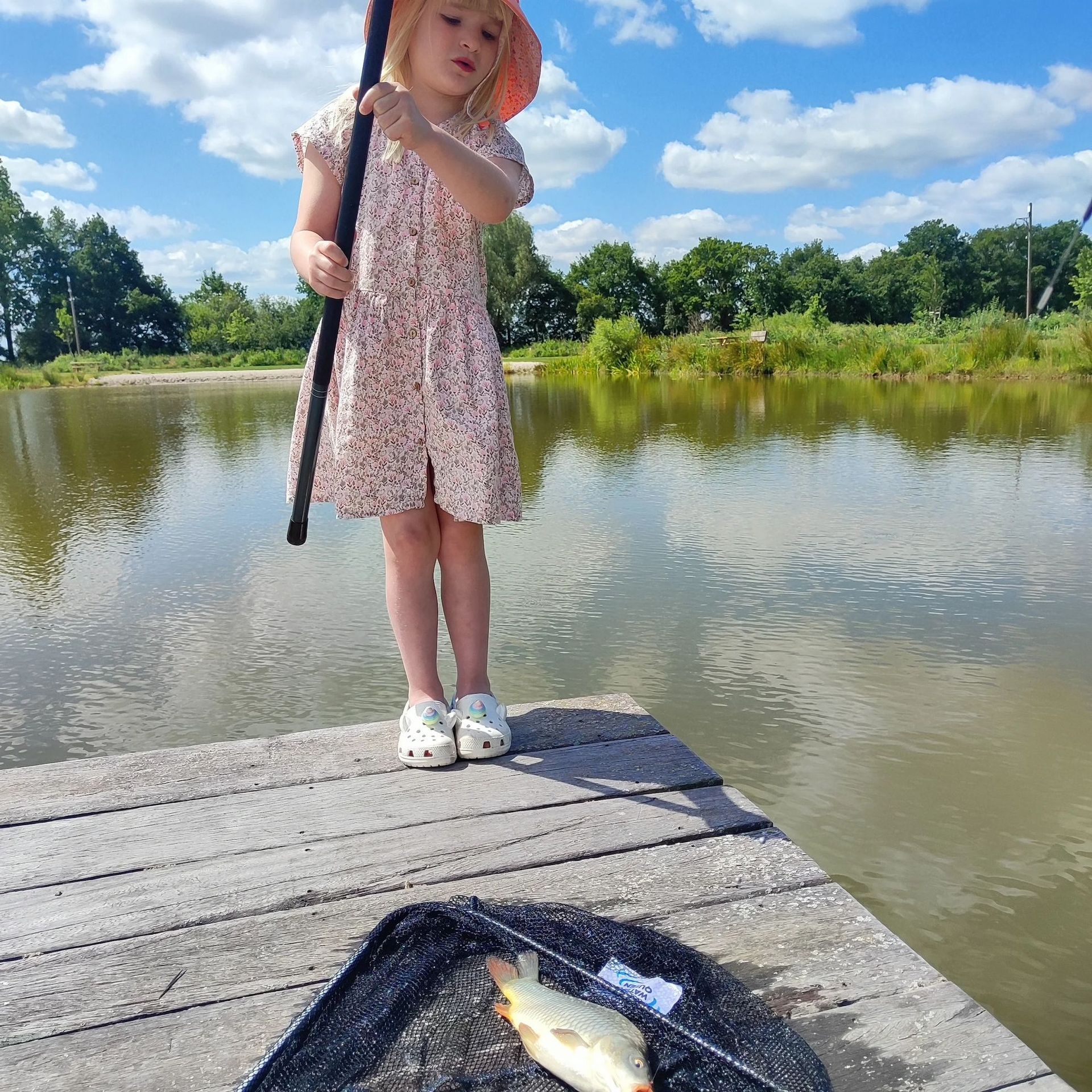 Meisje is aan het vissen vanaf een steiger, ze houdt een hengel vast en ving vis in een net. 